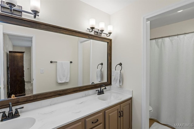 bathroom with double vanity, a sink, and toilet