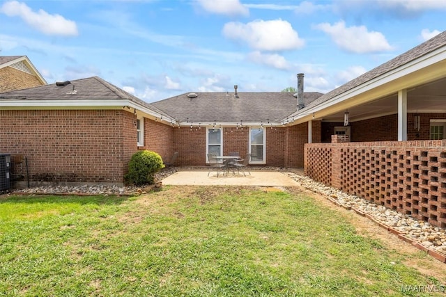 back of house with a patio area, brick siding, and a yard