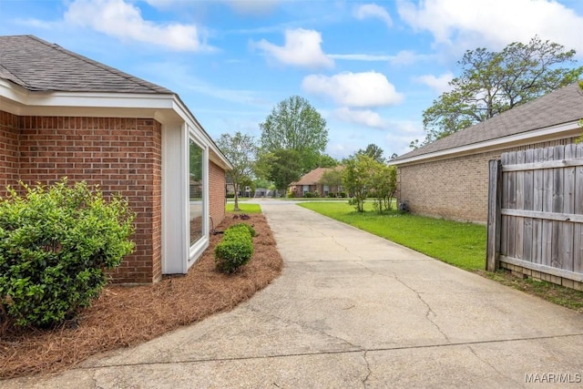 view of yard with concrete driveway and fence