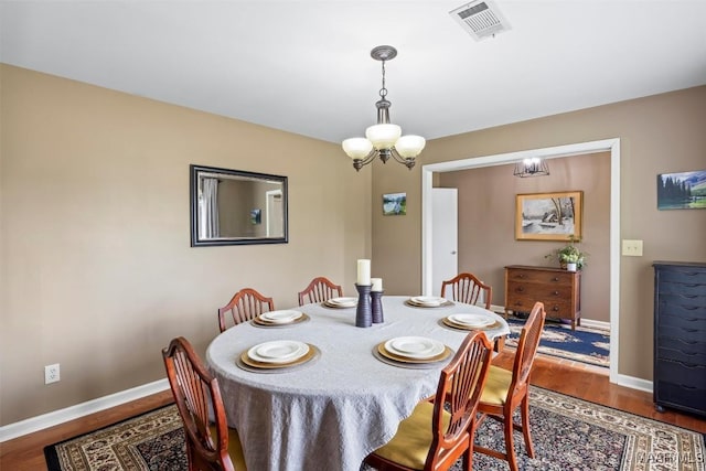 dining room with an inviting chandelier, visible vents, baseboards, and wood finished floors