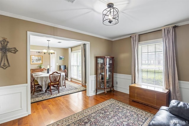 interior space with a wainscoted wall, crown molding, wood finished floors, and a chandelier