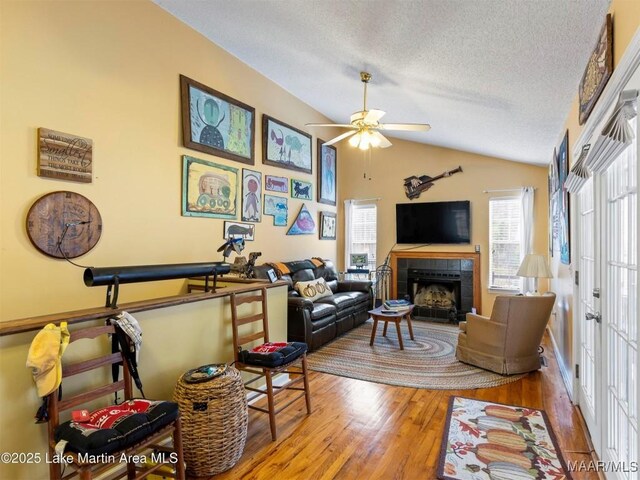 197 Maple Ridge Rd, Alexander City, AL 35010 - living area featuring vaulted ceiling, a textured ceiling, ceiling fan, a tile fireplace, and wood finished floors