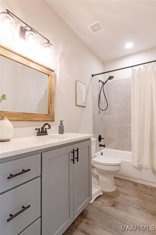 bathroom featuring wood finished floors, vanity, toilet, and shower / bath combo