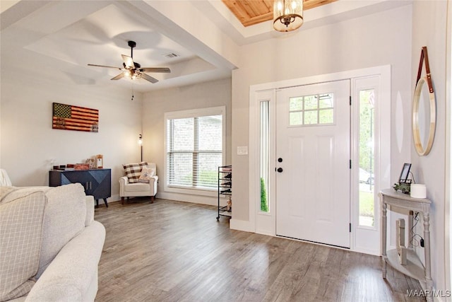 foyer with healthy amount of natural light, wood finished floors, a tray ceiling, and ceiling fan