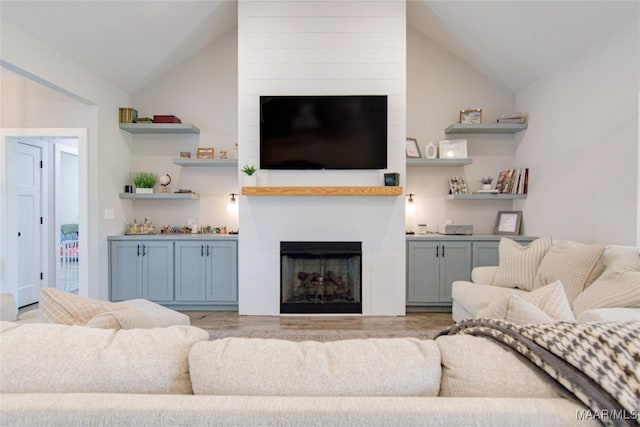 living area with a fireplace, lofted ceiling, and light wood-type flooring