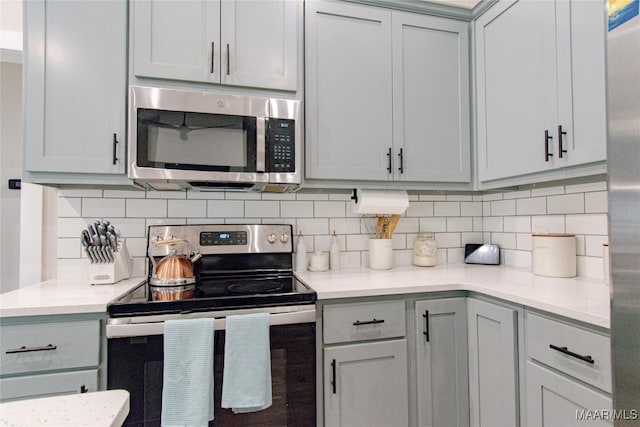 kitchen with appliances with stainless steel finishes, backsplash, light countertops, and gray cabinets