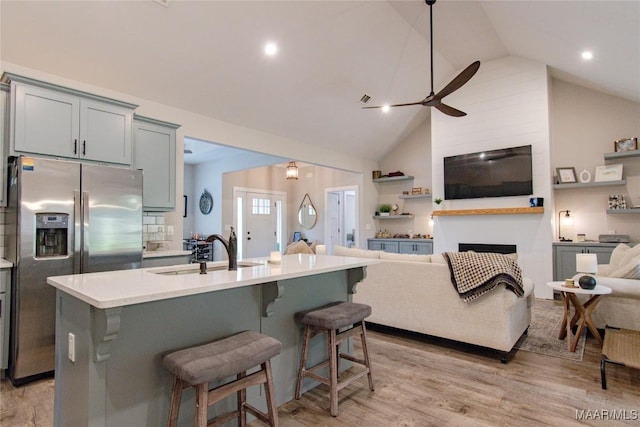 kitchen with open floor plan, stainless steel refrigerator with ice dispenser, a sink, a ceiling fan, and gray cabinets