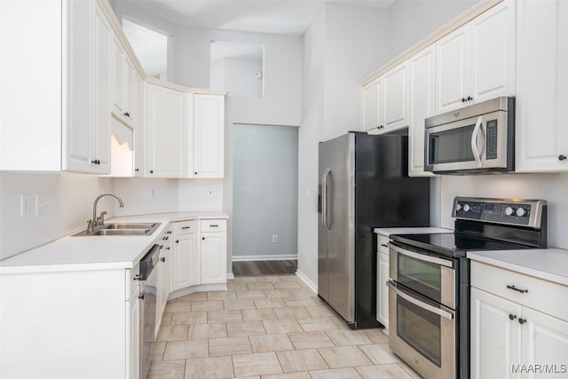 kitchen featuring stainless steel appliances, a sink, light countertops, and baseboards