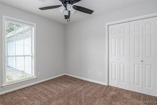 unfurnished bedroom with carpet flooring, a closet, baseboards, and ceiling fan