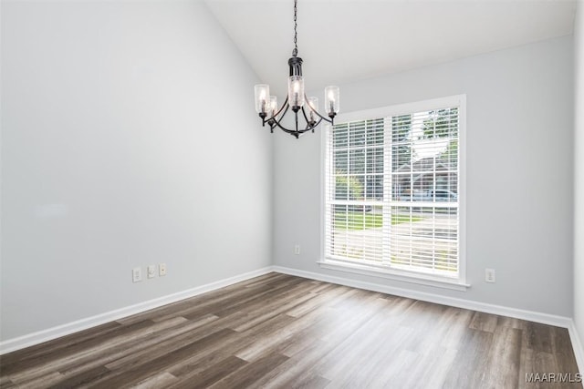 empty room featuring a chandelier, dark wood-style floors, baseboards, and lofted ceiling