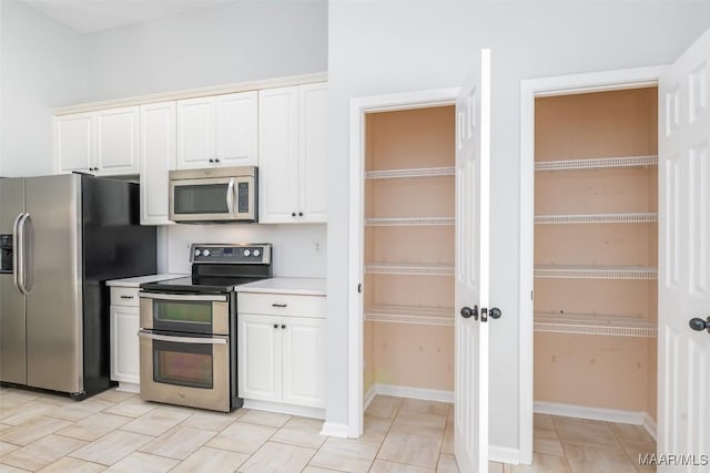 kitchen featuring stainless steel appliances, white cabinetry, and light countertops