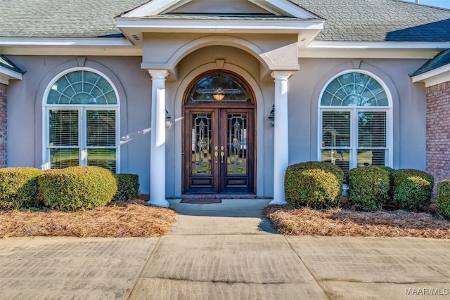 doorway to property with roof with shingles, stucco siding, and french doors