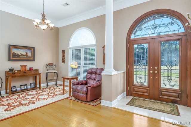 entryway with crown molding, french doors, decorative columns, and wood finished floors