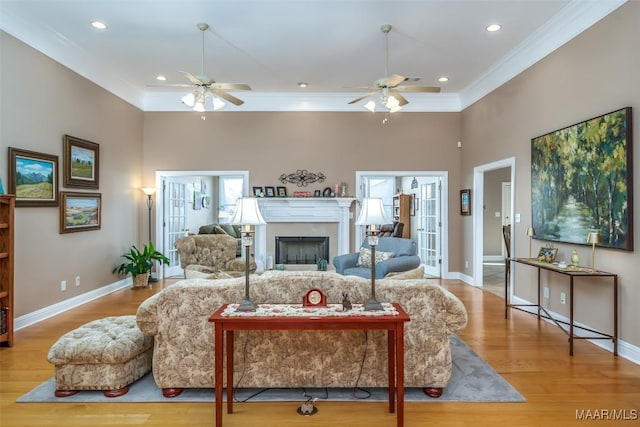 living area with baseboards, a ceiling fan, and wood finished floors