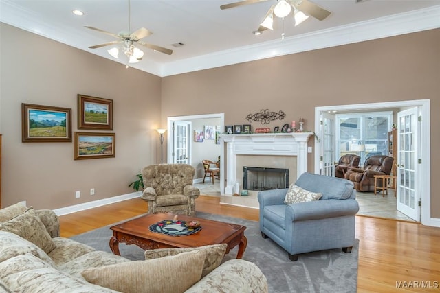 living room with visible vents, baseboards, ornamental molding, a ceiling fan, and wood finished floors