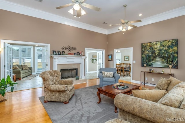 living room with baseboards, a ceiling fan, a fireplace, crown molding, and wood finished floors