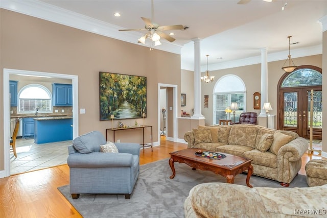 living area with ornate columns, plenty of natural light, and light wood-style floors