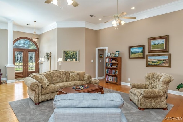 living area featuring crown molding, ornate columns, wood finished floors, and a ceiling fan