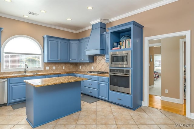 kitchen with a sink, premium range hood, blue cabinets, and stainless steel appliances