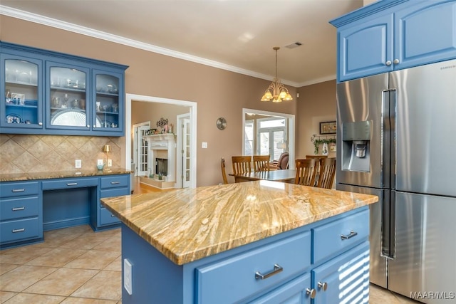 kitchen with tasteful backsplash, stainless steel fridge, a chandelier, visible vents, and blue cabinets