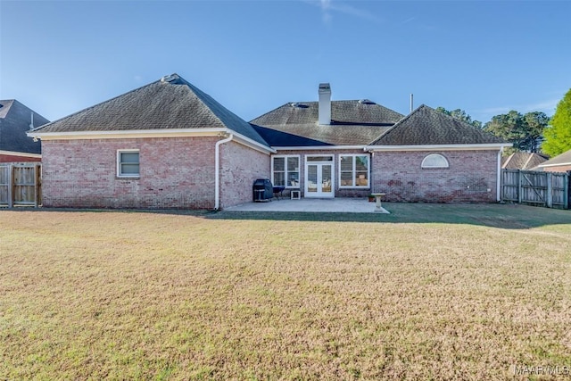 back of house featuring a yard, a patio area, fence, brick siding, and french doors