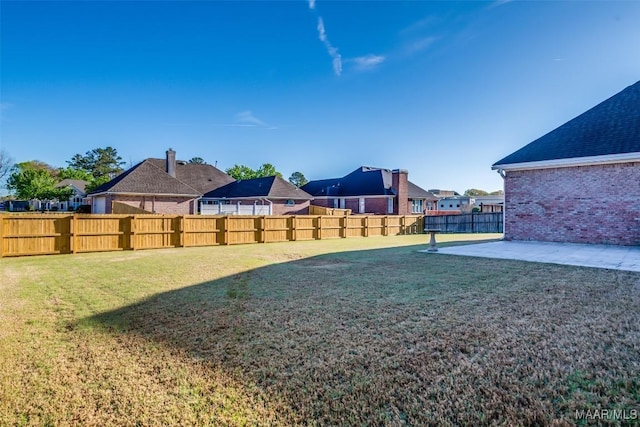 view of yard featuring a patio area, a fenced backyard, and a residential view
