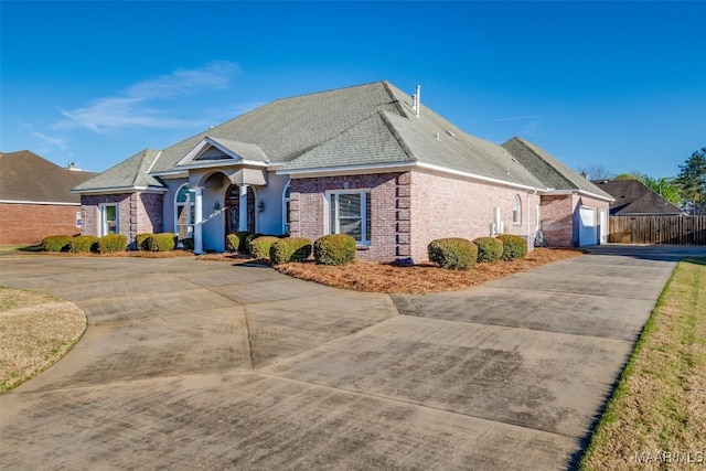 view of front facade featuring concrete driveway, a garage, fence, and brick siding