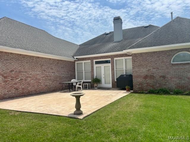 8681 Huntingdon Ridge Ln, Montgomery, AL 36117 - back of property with brick siding, a yard, a chimney, and a patio