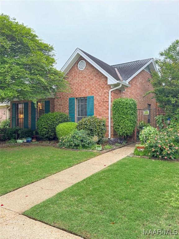 view of front facade featuring brick siding and a front lawn