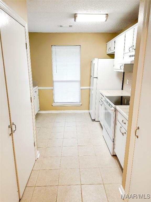 417 York Dr, Selma, AL 36701 - kitchen with electric range, light countertops, white cabinetry, a textured ceiling, and light tile patterned floors