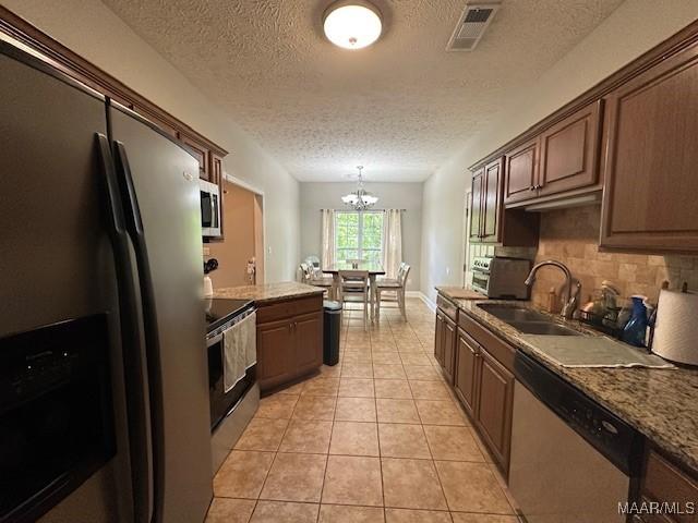 1518 White Cloud Dr, Deatsville, AL 36022 - kitchen featuring light tile patterned floors, visible vents, a sink, stainless steel appliances, and a notable chandelier