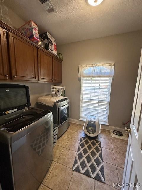 1518 White Cloud Dr, Deatsville, AL 36022 - laundry room with a textured ceiling, separate washer and dryer, visible vents, light tile patterned flooring, and cabinet space