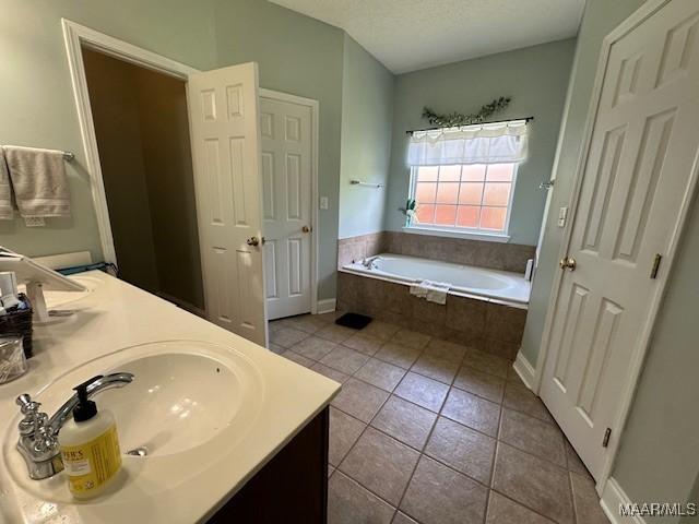 1518 White Cloud Dr, Deatsville, AL 36022 - bathroom with double vanity, tile patterned floors, a textured ceiling, a garden tub, and a sink