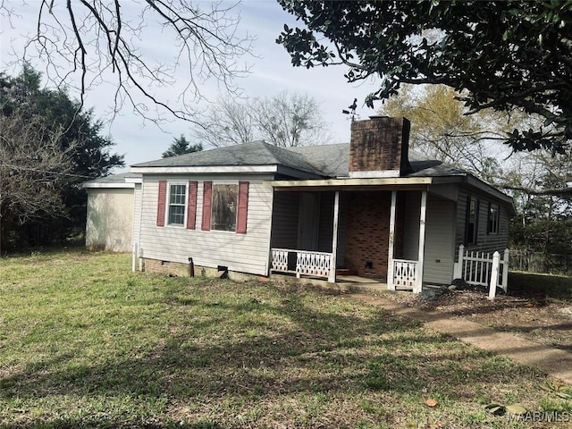 back of house featuring roof with shingles, a chimney, crawl space, a yard, and covered porch