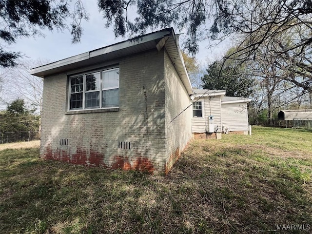 view of side of home featuring brick siding, fence, a lawn, and crawl space