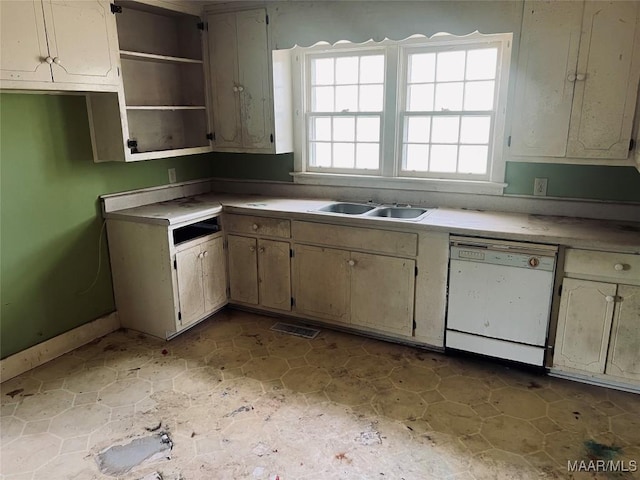 kitchen with baseboards, visible vents, a sink, and white dishwasher
