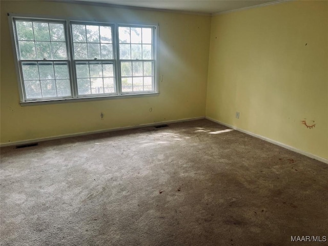 unfurnished room with carpet flooring, visible vents, baseboards, and crown molding