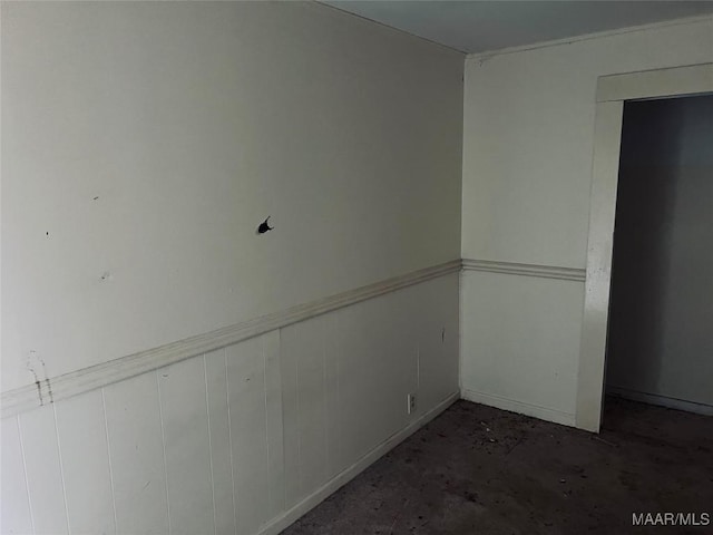 empty room featuring concrete flooring and a wainscoted wall