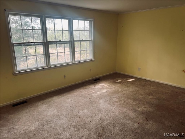 carpeted empty room featuring crown molding, baseboards, and visible vents