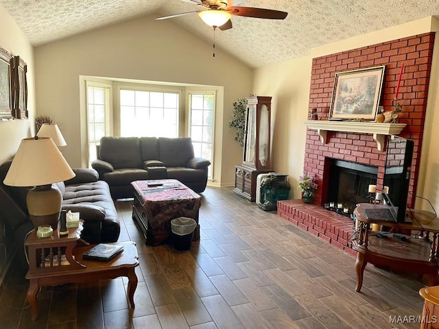 living room featuring ceiling fan, a fireplace, a textured ceiling, vaulted ceiling, and wood finished floors