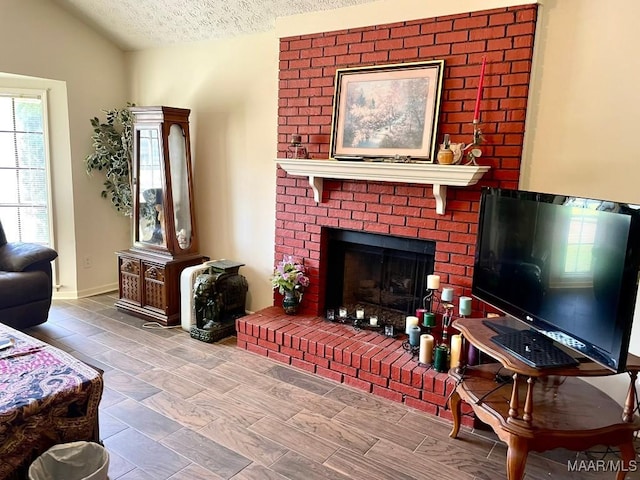 living room featuring vaulted ceiling, a fireplace, and a textured ceiling