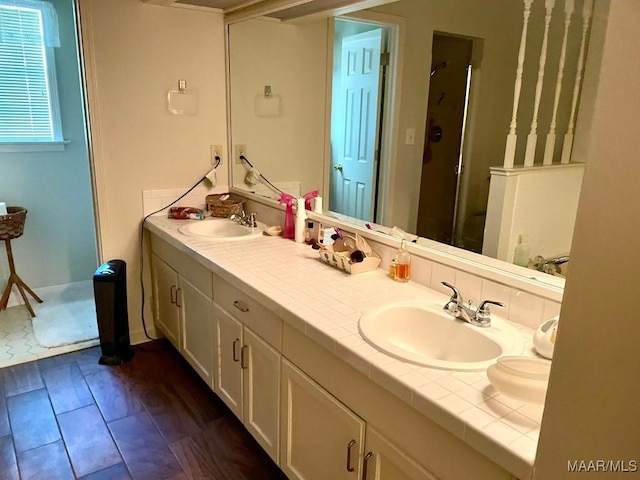 full bath with a shower stall, double vanity, a sink, and wood finished floors