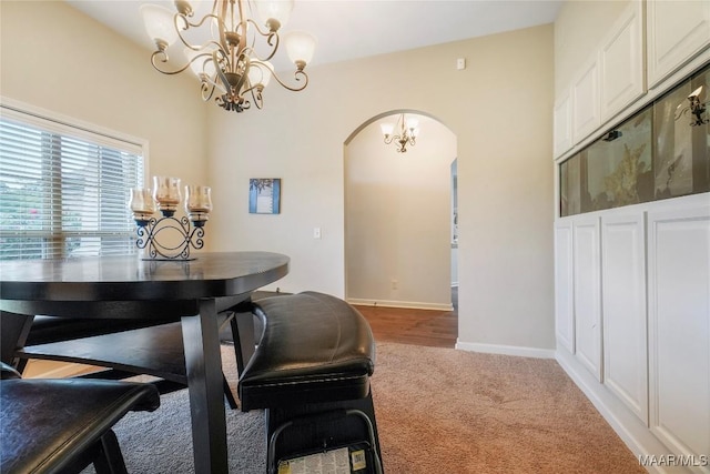 carpeted dining area with baseboards, arched walkways, and a chandelier