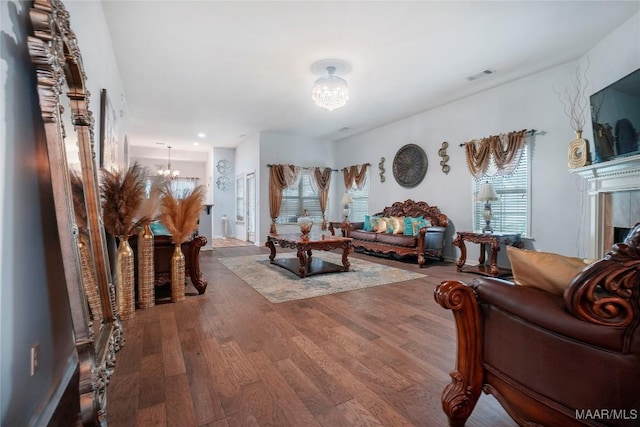 living area featuring wood finished floors, an inviting chandelier, and visible vents