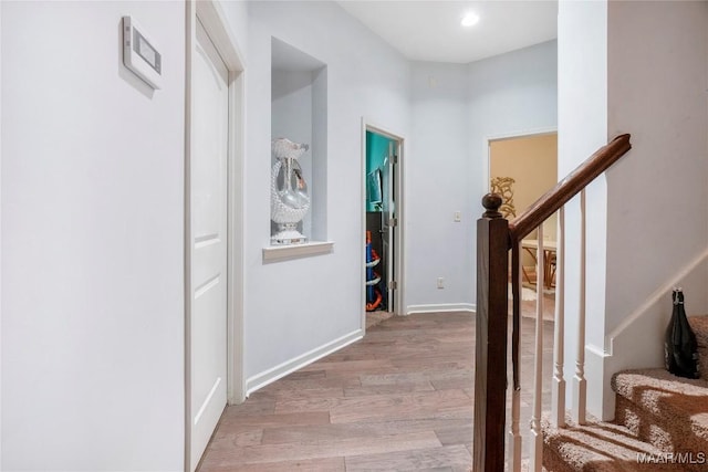 hallway featuring stairs, light wood-style floors, and baseboards