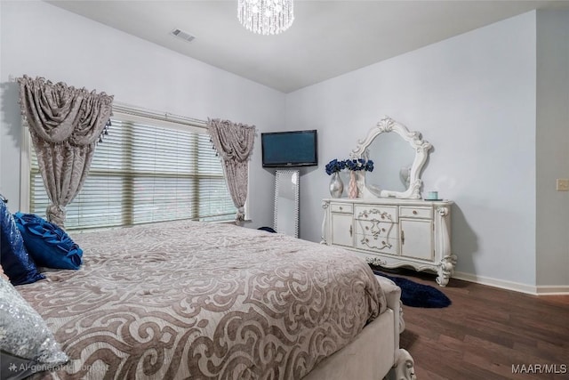 bedroom featuring visible vents, baseboards, an inviting chandelier, and wood finished floors