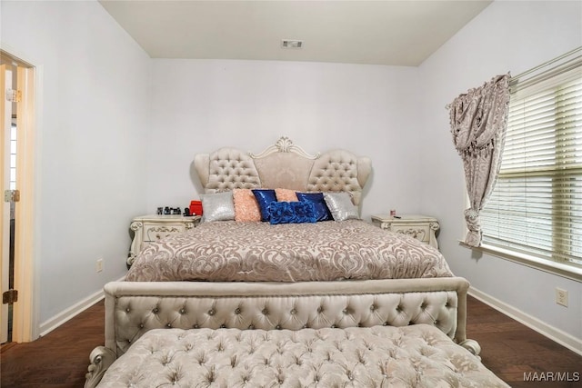 bedroom with visible vents, baseboards, and wood finished floors