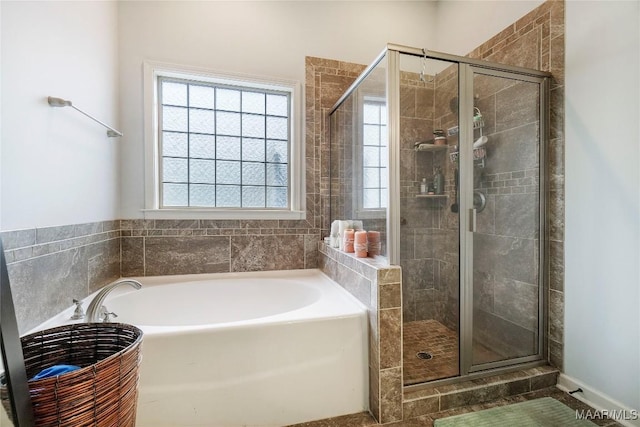 full bathroom with a shower stall and a bath