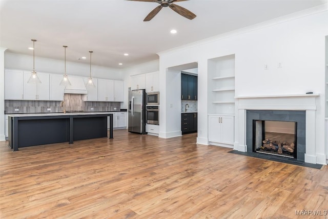 kitchen with light wood-type flooring, a ceiling fan, white cabinets, appliances with stainless steel finishes, and open floor plan
