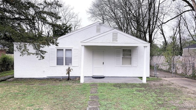 bungalow with a front lawn, fence, and stucco siding